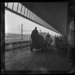 THO-3152-1 Met een elektrisch wagentje vervoeren mannen post op een perron van het nieuwe Centraal Station. Rechts ...