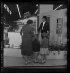 THO-3179 Een vrouw en twee kinderen kijken naar een pop op de stand van Nescafé, De stand is onderdeel van de ...