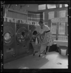 THO-3192 Een vrouw haalt de was uit een wasmachine van wasserette 'Zelfwas' aan de Delftweg 37.