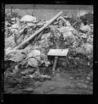THO-3205 Op een berg met afval ligt een bord met de tekst 'Vuil storten verboden'. Het afval ligt op het terrein van ...