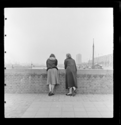 THO-433 Twee vrouwen kijken uit over de Leuvehaven vanachter een muurtje aan Plein 1940. Rechts de Schiedamsedijk.