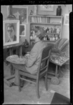 THO-471 Kunstenaar Cees Witters zit met penseel en palet bij een ezel met zelfportret in zijn atelier aan de ...