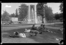 THO-662 Bezoekers van de manifestatie E '55 rusten uit op een grasveld in het Museumpark. Op de achtergrond een vijver ...