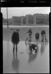 THO-744 In de regen spelen kinderen met zelfgemaakte bootjes in een regenplas bij de Gijsingstraat. Twee kinderen ...