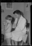 THO-910 Met een stethoscoop onderzoekt een arts een kind in het Sophia Kinderziekenhuis aan de Gordelweg.