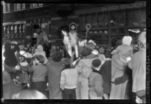 THO-931-1 Bij zijn aankomst op de Schiedamseweg zwaait Sinterklaas vanuit een koets naar zijn publiek.