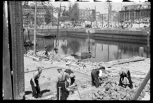 1980-5050 Mannen zijn bezig met het sorteren van stenen of het herstellen van wegdek aan de Blaak. Op de achtergrond ...