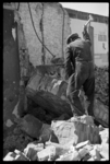 1980-5124 Een puinruimer is bezig met het stukslaan van een muur. Het gebouw is getroffen door het bombardement van 14 ...
