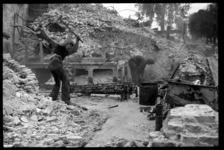 1980-5136 Puinruimers zijn bezig met het sorteren van stenen en puin in de restanten van de door het bombardement van ...