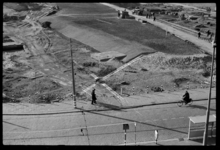 1980-5205 Wandelaars en een fietser langs het verwoeste en geruimde gebied bij de Hoogstraat en het Oostplein, gezien ...