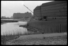 1980-5458 Door de nieuw aangelegde Delftsevaart vaart een eerste schip. Links het hoofdbureau van politie en rechts ...