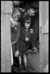 1980-5574 Operatie Manna. Twee jongetjes in kapotte kleding krijgen een stuk brood en chocolade van een agent. Ze zijn ...