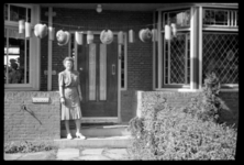 1980-5618 Mevrouw Grimeyer staat kort na de bevrijding voor de deur van haar met lampionnen versierde woning aan de ...