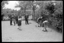 1980-5670 Vrouwen en meisjes met kortgeknipt haar moeten onkruid wieden op het pleintje voor de commandopost van de ...