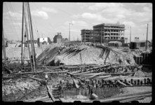 1980-5808 De werkzaamheden aan de nieuwe Leuvekolk. Oude heipalen worden verwijderd. Op de achtergrond de nieuwbouw ...