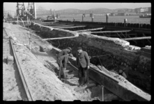 1980-5812 Reparatie van kademuren langs de Boompjes. Bouwvakkers staan in een afgegraven stuk grond. Rechts een oude ...