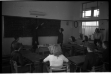 1009-01 Docent en kinderen in een klaslokaal van een school van de Ammanstichting. De stichting verzorgde onderwijs ...