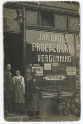 2014-128-2 Eigenaren heer en mevrouw Groos-Timmermans (in deuropening) en klanten met bierglas in de hand poseren voor ...