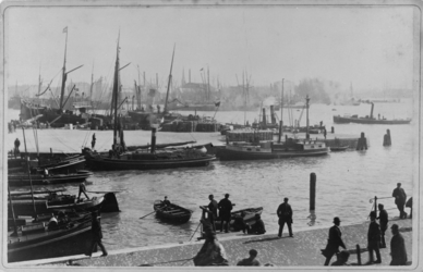 VII-269-2 Zicht op de mond van de Leuvehaven, met heel wat schepen in het water. Op de kade vooraan lopen enkele mensen.