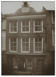 XXV-357 Man in de deuropening in de Sint-Jacobsstraat bij zijn winkel.