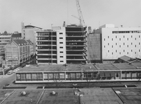 1974-1224 De bouw van de parkeergarage van magazijn De Bijenkorf (rechts) aan de Hennekijnstraat. Op de voorgrond ...