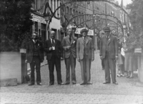 1974-1690 Leiders van het feestcomité staan voor de versierde Helmersstraat, hoek van de Kruisstraat. Op de foto (van ...