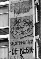 1975-1543 Gezicht op de verschillende malen beschilderde plaats voor reclame aan de gevel van het hoekhuis Tiendstraat ...