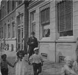 1977-210 De oostzijde van de Havenstraat. De heer L. Busemeijer staat voor een paar wandelende kinderen.