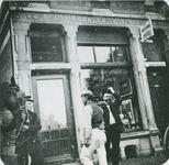 1977-30 Drie mannen voor de slijterij aan westzijde van de Havenstraat 11. Op de gevel: Stoomdistilleerdery en Likeurstokery.