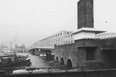 1977-76 De Willemsbrug en rechts de spoorbrug over de Nieuwe Maas, aan de zijde van de Maaskade op het Noordereiland. ...
