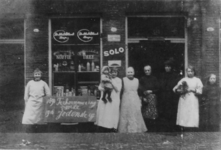 1980-1900 Kruidenier mevrouw E. Kerkhof-Bos en personeel voor haar winkel aan de Jodensteeg.Op het bord links staat: ...