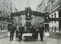 1980-4614 Op Koninginnedag versierde straat met de feestcommissie, aan de ingang: zittend midden dhr. Kramers, rechts ...