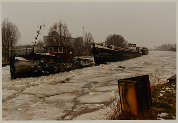 1987-244 De ijsbreker Moos voor een aantal binnenvaartschepen naderen de spoorbrug over de Delfshavense Schie. Op de ...