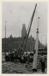 IX-1343-19-15-01 Het plaatsen van een lichtmast op het Hofplein tijdens de aanleg van het plein.Op de achtergrond het ...