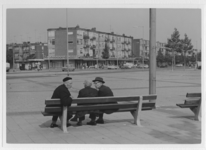 IX-2922-02 Drie bejaarden op een bankje op het Slingeplein. Op de achtergrond woningen en winkels aan de Slinge.