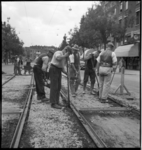 1259 Arbeiders werken met scheppen en ander gereedschap tussen de tramrails aan het asfalteren van de Vierambachtsstraat.