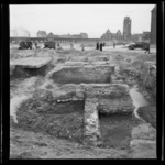 1568 Blootgelegde fundamenten van de Delftsche Poort bij het Hofplein. Op de achtergrond verkeer en de Grote of Sint ...
