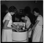 16400 Drie leerlingen werken met een wasmachine met wringer tijdens een les bij de huishoudschool in de Talingstraat.