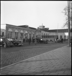 1737 Station Delftsche Poort aan het Stationsplein. Voor de ingang van het station voetgangers, fietsers en geparkeerde ...