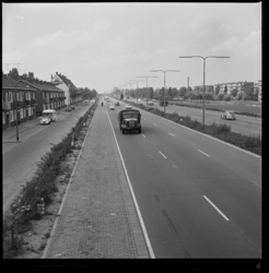 19571 Rijksweg 13 bij Overschie. Op de vluchtstrook staat een man. Links van de weg woonhuizen, rechts een park.