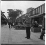 19718 Een toerist met een camera op de Lijnbaan op de kruising van het Stadhuisplein en de Korte Lijnbaan. Rechts het ...