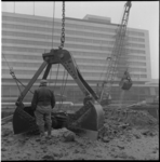 21065 Hijskranen vervoeren zand bij de aanleg van de metro op het Weena. Op de achtergrond het Hilton Hotel.