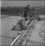 21207 Twee werknemers in overall op het dak van een huis bezig bij de bouw van woningen in Lombardijen of Groot-IJsselmonde.