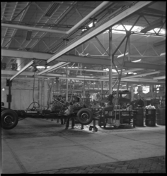 2188 Twee monteurs werken aan het chassis van een auto in de werkplaats van autofabriek van Kaiser-Frazer Fabrieken ...