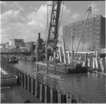 22912 Bouw van de Admiraliteitsbrug over het Boerengat. Vanaf een ponton worden met behulp van een stoomhijskraan ...