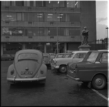34112 Geparkeerde auto's op de Sint-Laurensplaats bij het gebouw De Heuvel. Te midden van de auto's het standbeeld van ...