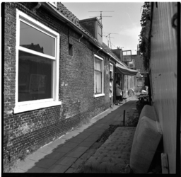 41533 Bewoners voor de deur van hun woningen aan een hofje aan de Overschiese Dorpsstraat.