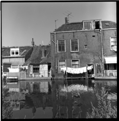 41544 De Rotterdamse met Schie met aan de overzijde woningen aan de Zestienhovensekade. Bij een van de woningen hangt ...