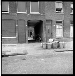 41730 Toegang tot een hofje bij de Dirk Smitsstraat 50 in Rubroek. Op straat staan vuilnisemmers klaar om geleegd te worden.