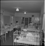 5730 Interieur van de Kinderkliniek 'Beatrix-Irene' aan de Schulpweg. Twee zusters verzorgen kinderen die in de bedjes ...